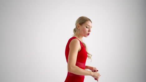 A-woman-in-a-red-tracksuit-looking-into-the-camera-conducts-training-and-tells-and-shows-exercises-from-yoga-or-Pilates-on-a-white-background.-Yoga-instructor-shows-exercises-for-home-classes